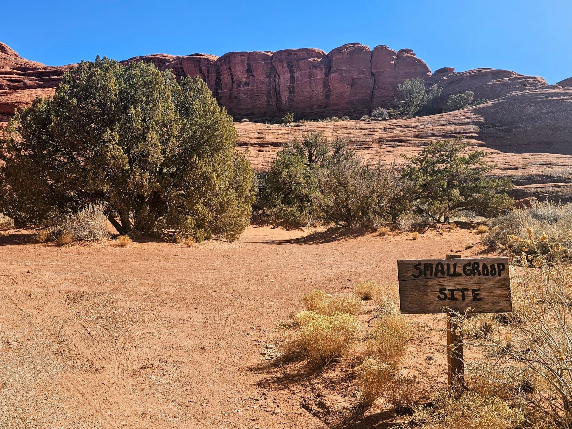 The group site, its hand-painted sign in the foreground and a red rock wall behind